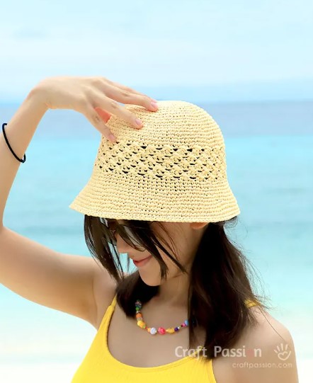 A woman on a the beach wearing a crochet bucket hat