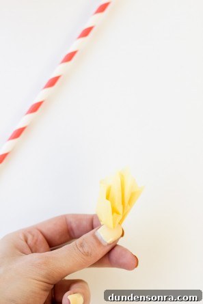 Someone holding yellow paper and a straw
