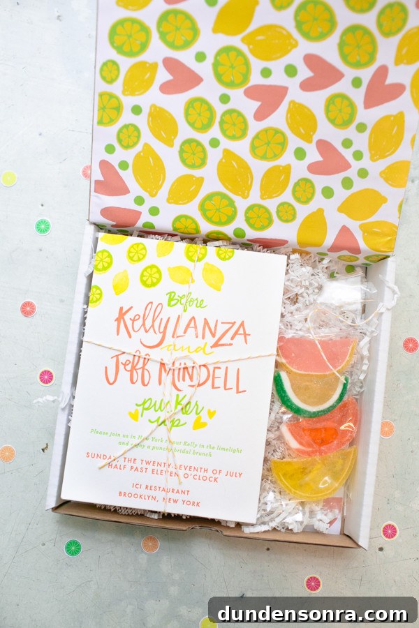 Overhead shot of a citrus designed box with a bridal shower invitation inside with citrus candies. 