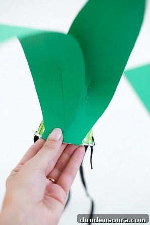 green paper leaves being glued to paper cup
