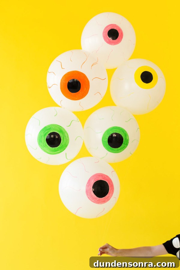 How to Make Spooky Eyeball Balloons for Halloween Decorations 3 Eyeball balloons in front of a yellow wall