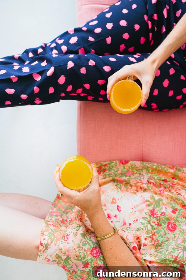 Two women holding orange drinks