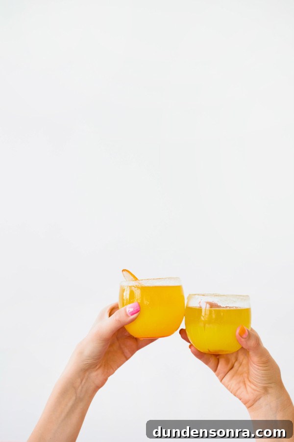 Two people holding two orange drinks