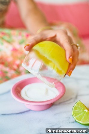 Someone holding a cup with an orange drink in it over a bowl 