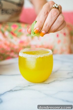 A person squeezing a lime into an orange drink