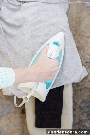 DIY Donut Elbow Patches: How to Sew Cute Patch Repairs 7 Someone ironing on grey fabric