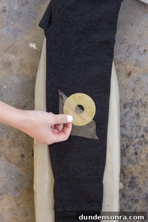 Someone putting a circular gold item on black fabric