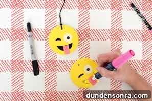 Someone drawing an emoji face on a ornament 