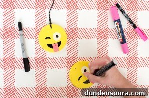 Someone drawing an emoji face on a ornament 