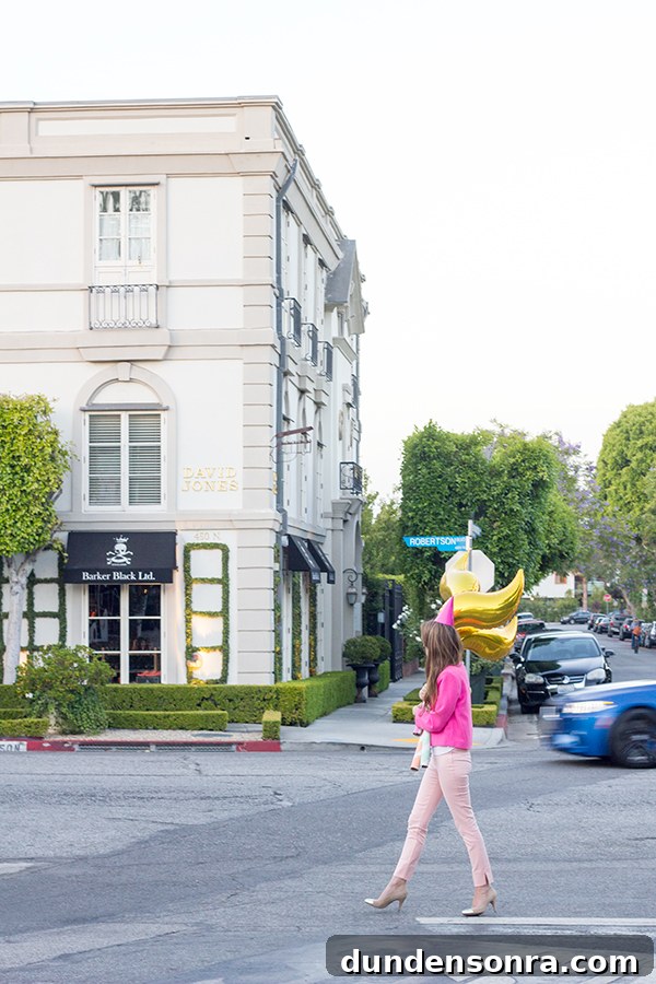 A woman holding a gold balloon walking across a street