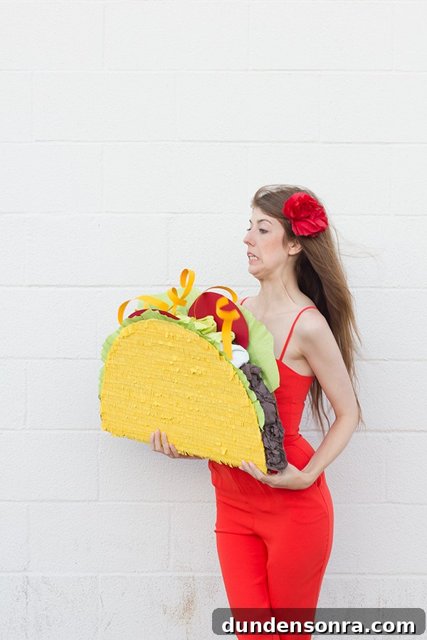 A woman wearing a red dress and holding a taco piñata 