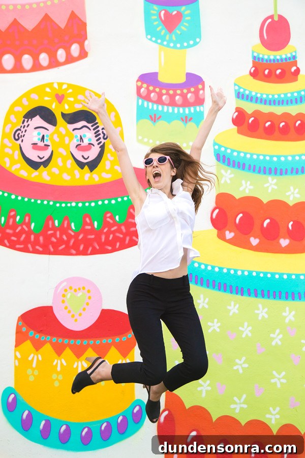 A woman in front of a mural with cakes and faces 