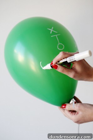 Someone drawing on a green balloon