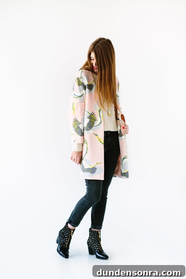 A woman in jeans, a sweater, and a pink coat