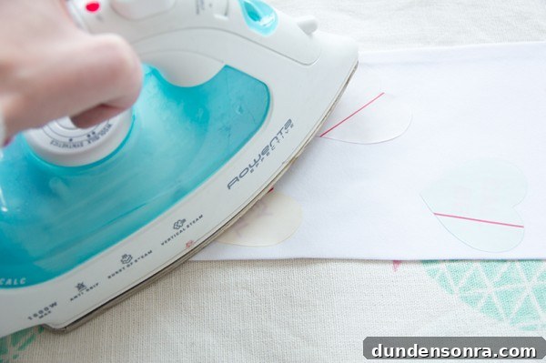 Someone ironing something onto white fabric 