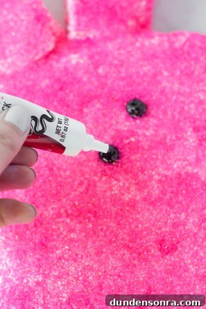 Someone putting black frosting on a pink cake