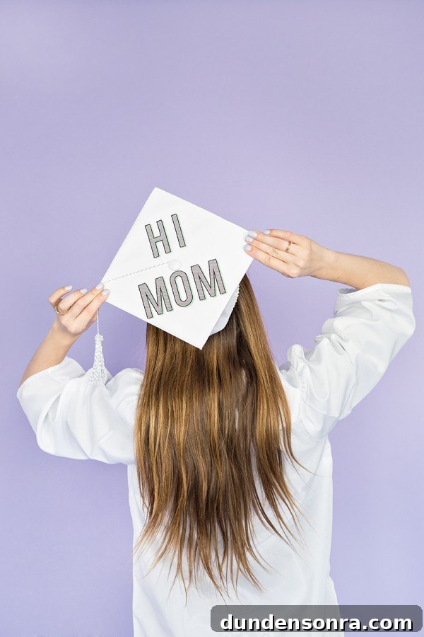 Someone wearing a graduation cap that says "hi mom"