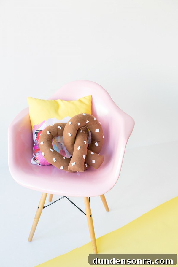 A pink chair with a pretzel pillow