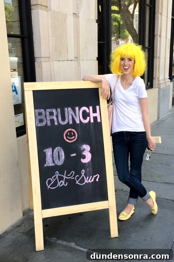 A woman in a wig standing next to a sign
