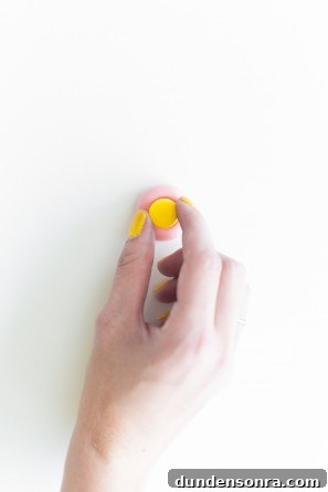 A woman putting a yellow dot on a pink snack