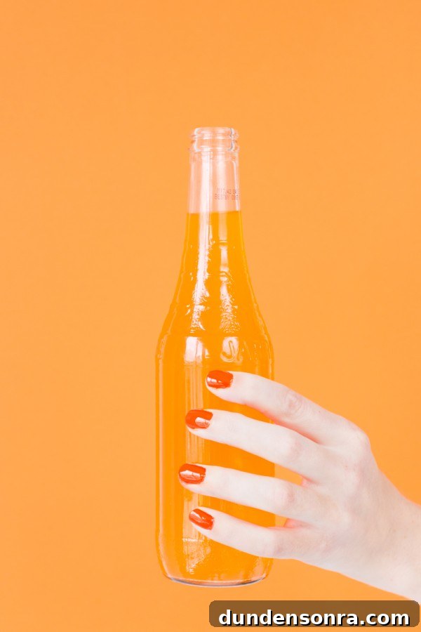 Someone holding a bottle with orange liquid
