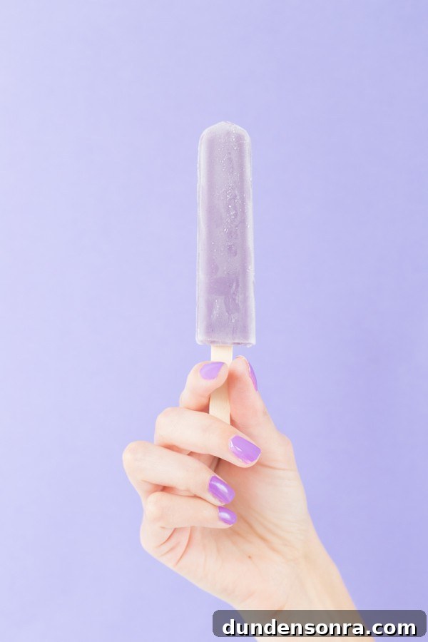 A woman holding a purple popsicle