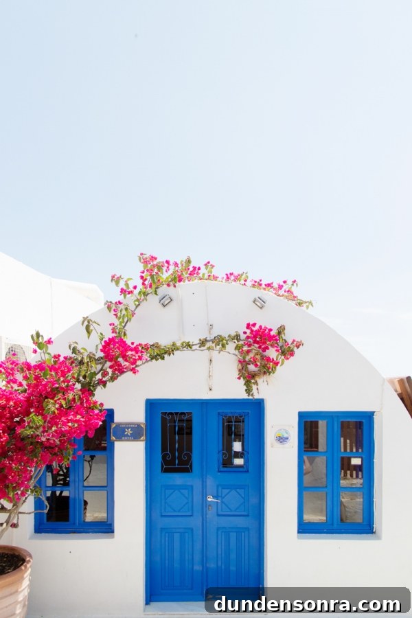 Honeymoon in Santorini: Meet the Mindells' Romantic Getaway 25 A white building with blue doors and flowers