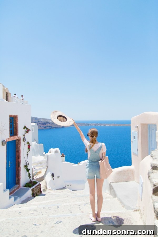Honeymoon in Santorini: Meet the Mindells' Romantic Getaway 27 A woman holding a hat looking at the sea