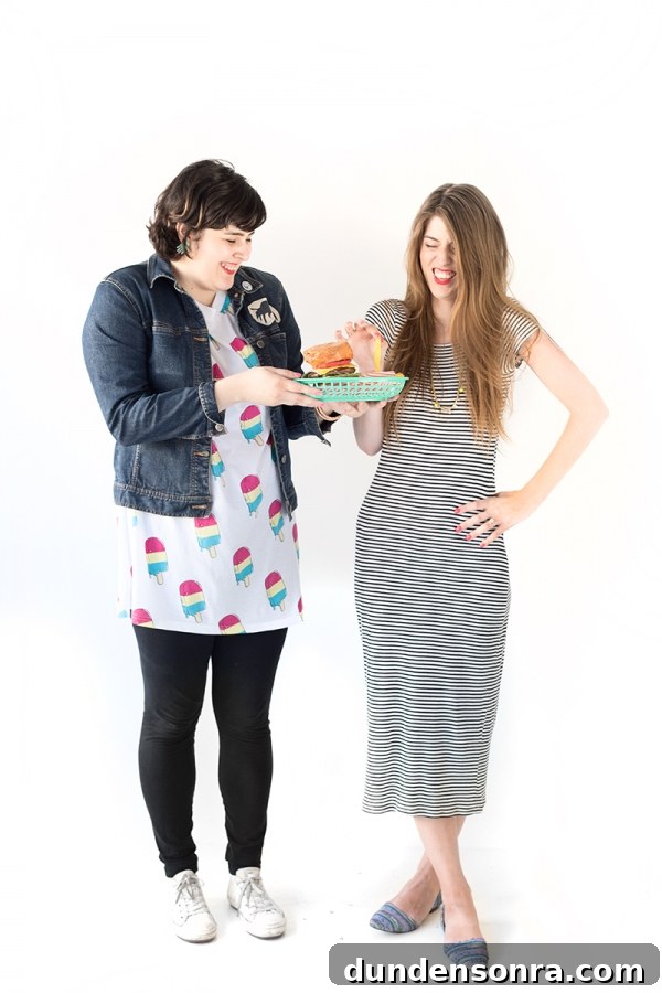 Two woman wearing dresses and holding a tray