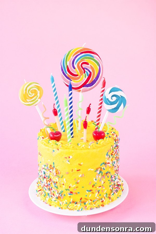 A yellow cake with lollipops and candles 