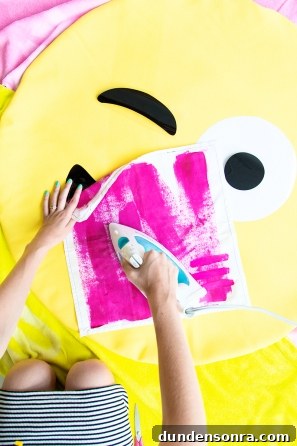 Someone ironing pink fabric on an emoji pillow