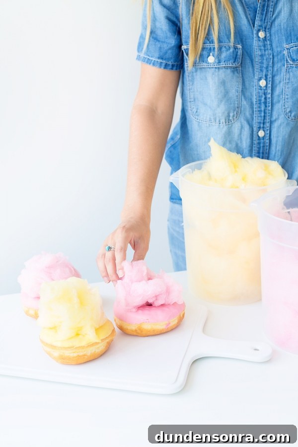 Someone putting cotton candy on a donut