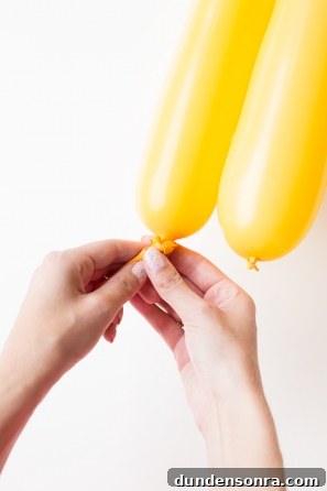 Someone tying a yellow balloon