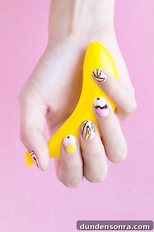 Banana Split Nail Art Ideas: Fun DIY Manicure Designs 11 Someone with pink and yellow nails holding a fake banana