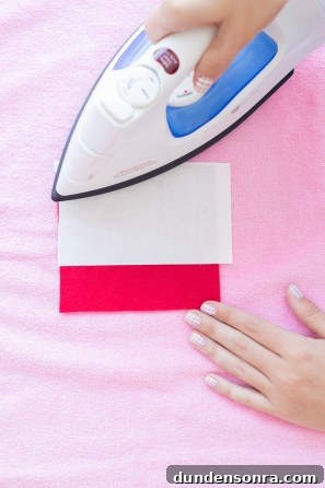 Someone ironing a red patch on pink fabric