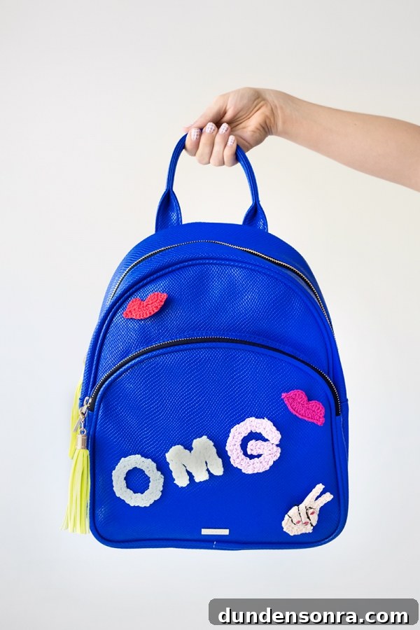 Someone holding a blue backpack that says "omg"