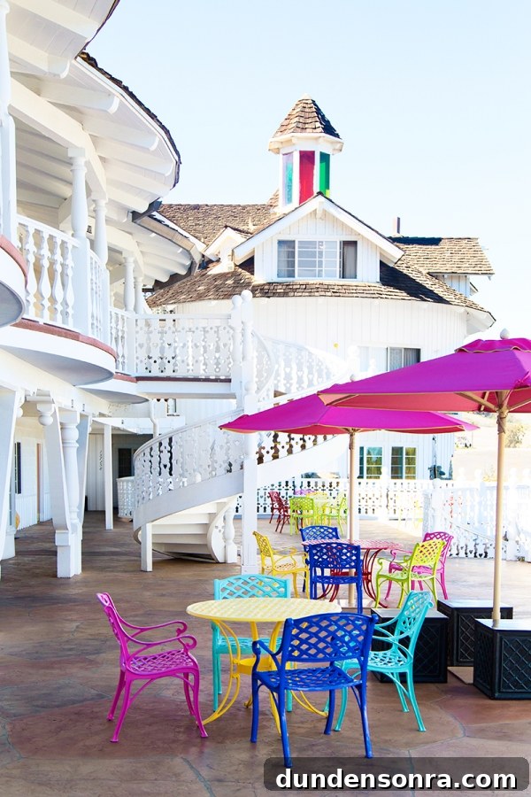 A white building with colorful chairs and tables outside of it