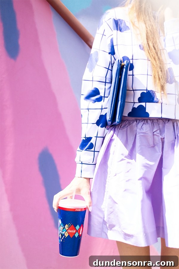 3 Bold Colorful Fall Outfits to Elevate Your Wardrobe 13 A close up of a woman wearing a white and blue shirt and purple skirt