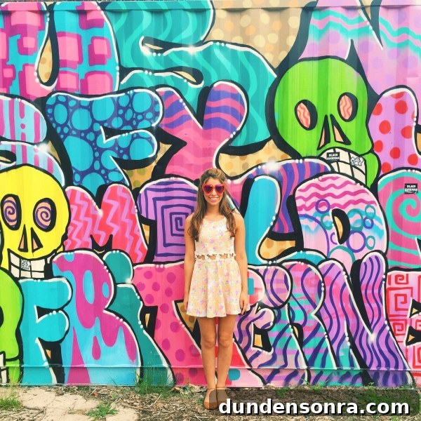 A woman standing in front of a colorful mural