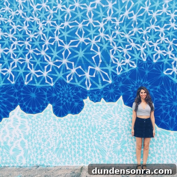 A woman standing in front of a blue mural