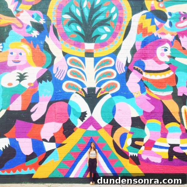 A woman standing in front of a colorful mural