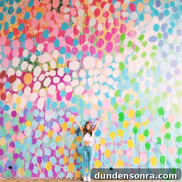 A woman standing in front of a colorful mural