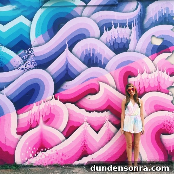 A woman standing in front of a colorful mural