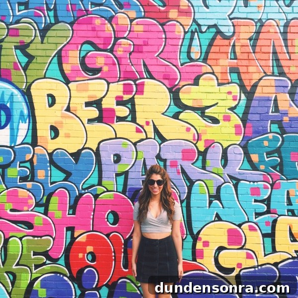A woman standing in front of a colorful mural