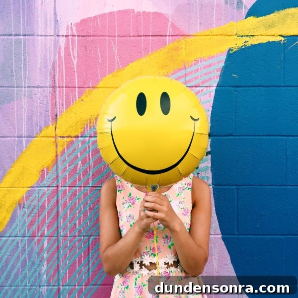 A woman holding a smiley face balloon