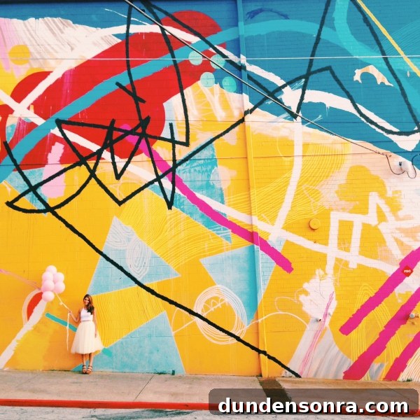 A woman standing in front of a colorful mural