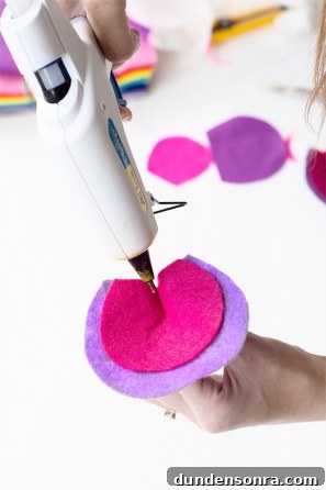 Someone gluing something on a pink and purple circle