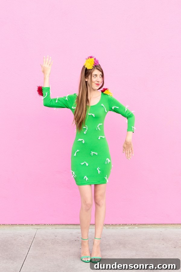A woman wearing a cactus costume in front of a pink wall