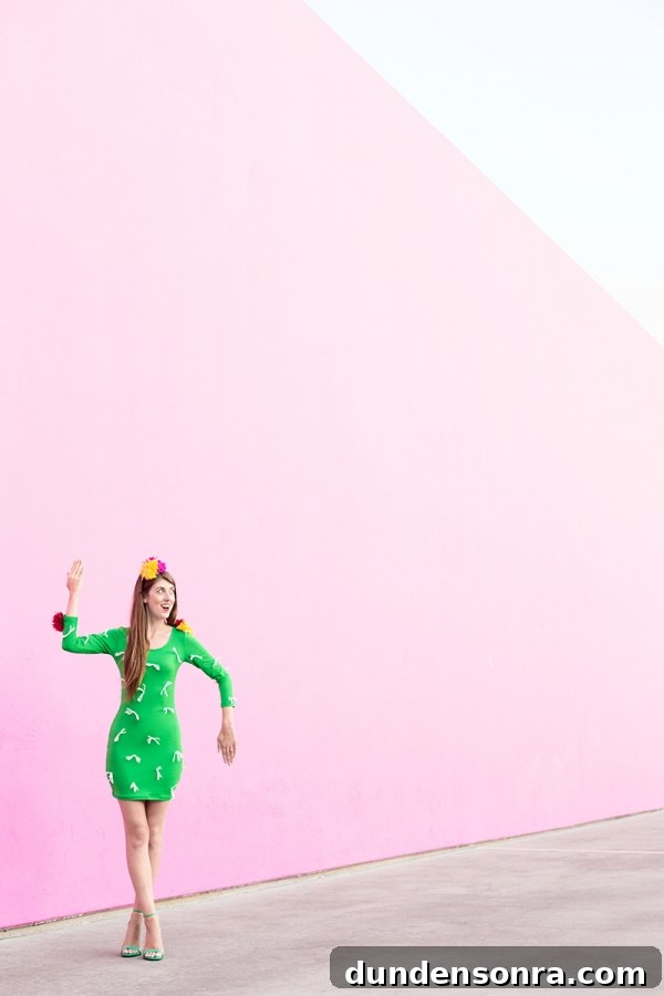 A woman wearing a cactus costume in front of a pink wall