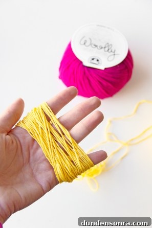 Someone holding yellow string and purple yarn